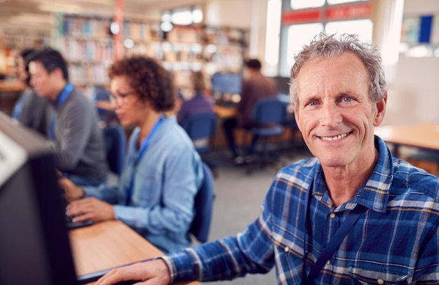 Portret mężczyzny dojrzałego dorosłego ucznia w klasie, pracującego przy komputerach w bibliotece uniwersyteckiej