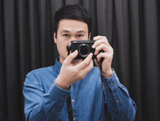 Portret mężczyzny fotografującego przed czarną zasłoną