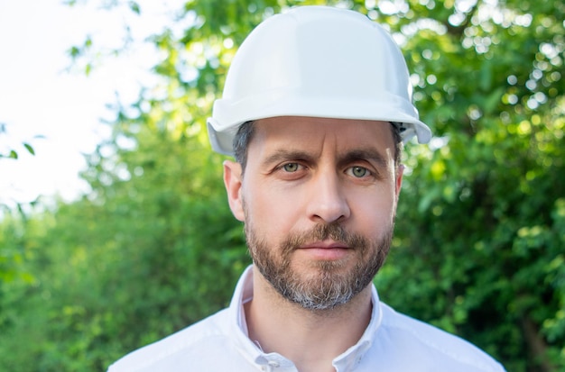 Portret mężczyzny inżyniera noszącego kask na zewnątrz naturalnego tła