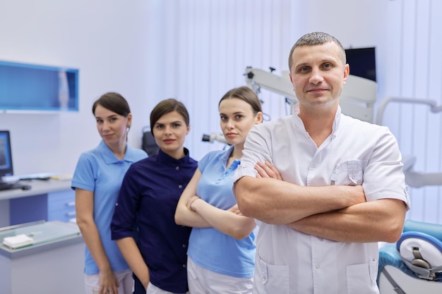 Portret mężczyzny lekarza dentysty i kobiet stażystów w gabinecie stomatologicznym. Personel, medycyna, stomatologia i opieka zdrowotna