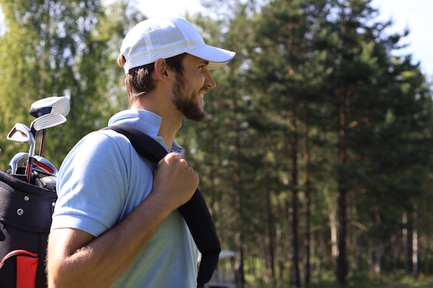 Portret mężczyzny w golfa spaceru z torbą na ramię.
