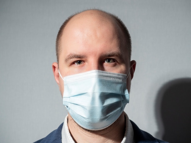 Portret mężczyzny w średnim wieku, ubranego w maskę medyczną i garnitur. Patrzy w kamerę