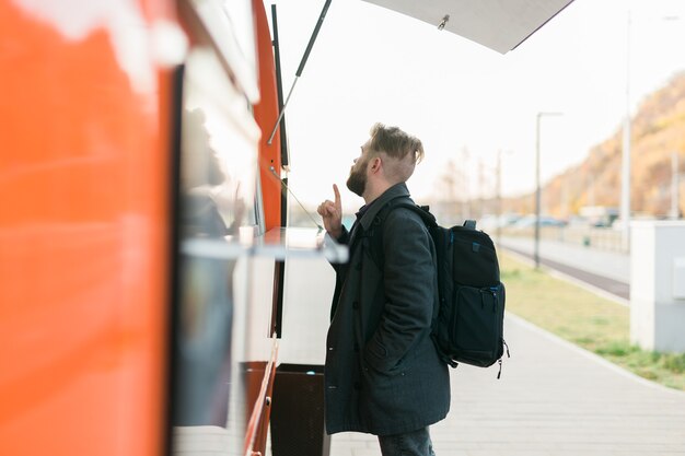 Portret mężczyzny wybierającego fast food w ciężarówce z jedzeniem w przemyśle spożywczym ulicznym i ulicznym