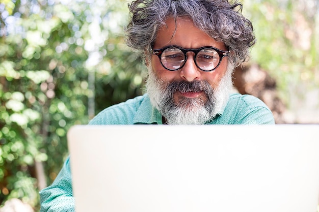 Portret mężczyzny z siwymi włosami i brodą pracującego na laptopie