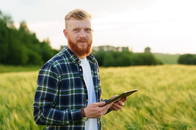 Portret mężczyzny z tabletem stojącym na polu pszenicy Dobre zbiory w gospodarstwie ekologicznym