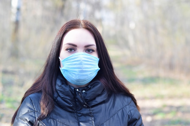 Portret młoda brunetki kobieta w błękitnej ochronnej masce outdoors