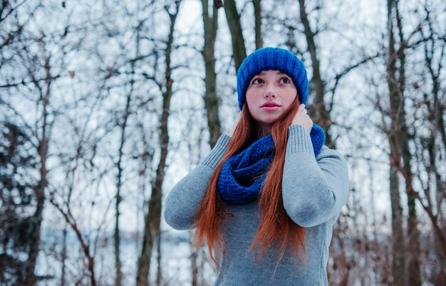 Portret młoda czerwona włosiana dziewczyna jest ubranym przy błękitnym trykotowym wełna kapeluszem, szalikiem w zima dniu z piegami i.