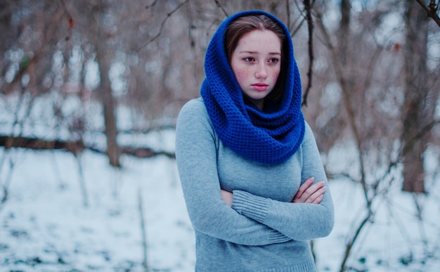Portret młoda czerwona włosiana dziewczyna jest ubranym przy błękitnym trykotowym wełna szalikiem w zima dniu z piegami.