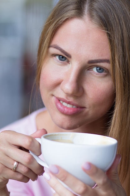 Zdjęcie portret młoda dziewczyna która pije cappuccino od dużej białej filiżanki