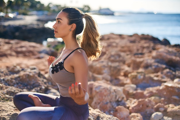 Portret młoda kobieta medytuje przy plażą przeciw pięknemu błękitnemu morzu.