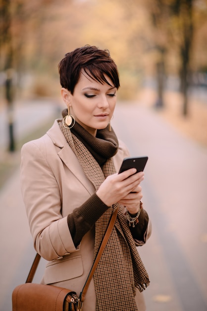 Portret młoda kobieta używa telefon na ulicie