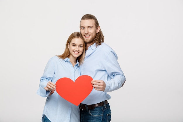 Portret młoda szczęśliwa para w miłości trzyma czerwieni papierowego serce.