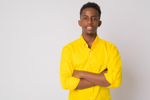 Portret młodego afrykańskiego biznesmena z Afro włosów na sobie żółtą koszulkę przed białą ścianą