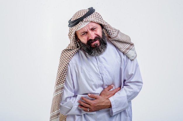 Portret młodego arabskiego muzułmanina wycisnąć brzuch za ból brzucha, na białym tle.