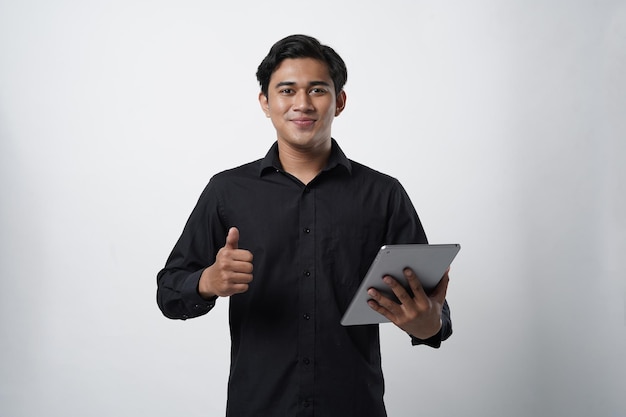 Portret młodego azjatyckiego faceta trzymającego urządzenia cyfrowe, uczącego się i uczącego za pośrednictwem witryn internetowych