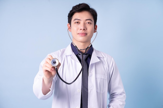 Portret młodego azjatyckiego lekarza płci męskiej na niebieskim tle