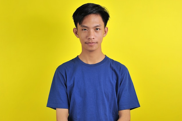 Portret młodego azjatyckiego mężczyzny z pewnym uśmiechem, odizolowany na żółto