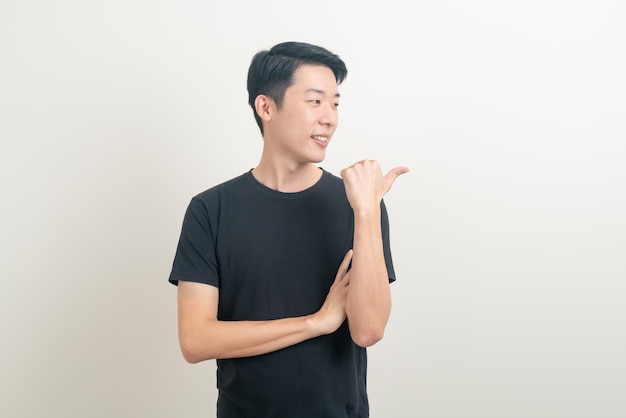 portret młodego azjatyckiego mężczyzny z ręką wskazującą lub przedstawiającą na białym tle