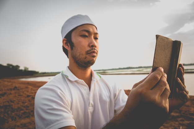 Portret młodego azjatyckiego muzułmańskiego mężczyzny modlącego się na zachód słońcaKoncepcja festiwalu RamadanCzytanie książki