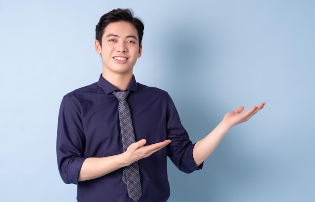 Portret młodego biznesmena z Azji pozuje na niebieskim tle