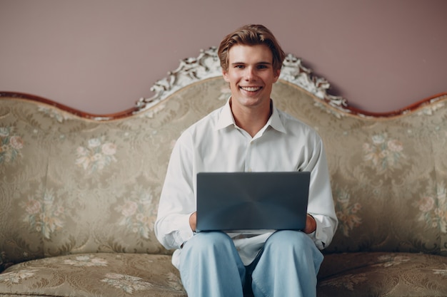 Portret młodego człowieka siedzącego z laptopem w studio.