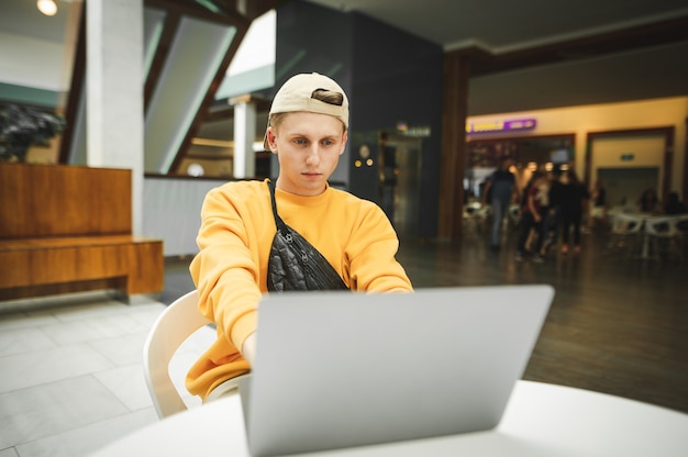 Portret młodego człowieka, skoncentrowanego na pracy na laptopie