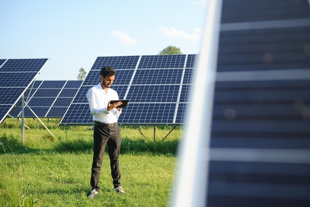 Portret młodego indyjskiego technika lub menedżera w formalnych ubraniach stojącego z panelem słonecznym odnawialna energia człowiek stojący z skrzyżowanymi ramionami kopiować przestrzeń