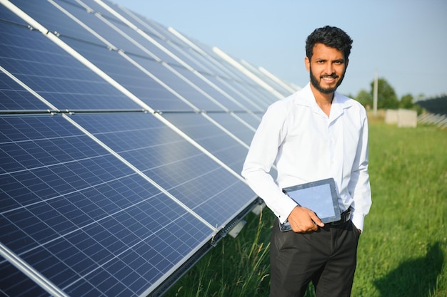 Portret młodego indyjskiego technika lub menedżera w formalnych ubraniach stojącego z panelem słonecznym odnawialna energia człowiek stojący z skrzyżowanymi ramionami kopiować przestrzeń