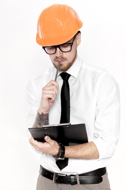 Portret młodego inżyniera budowlanego w pomarańczowym kasku z folderem na białym tle