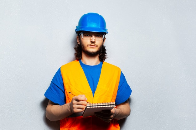 Portret młodego inżyniera pracownika noszącego sprzęt budowlany bezpieczeństwa, trzymającego notebook