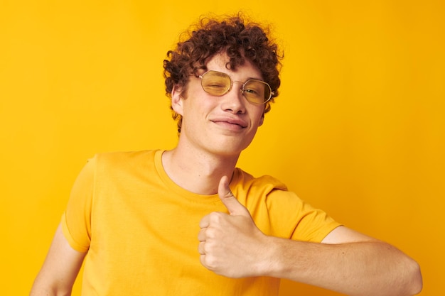 Portret młodego kręconego mężczyzny w stylowych okularach w żółtej koszulce pozuje niezmieniony styl życia