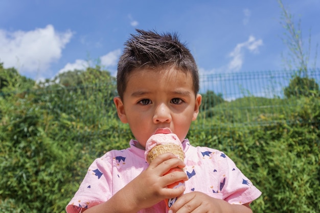 Portret młodego latynoskiego dziecka jedzącego lody w parku w słoneczny dzień