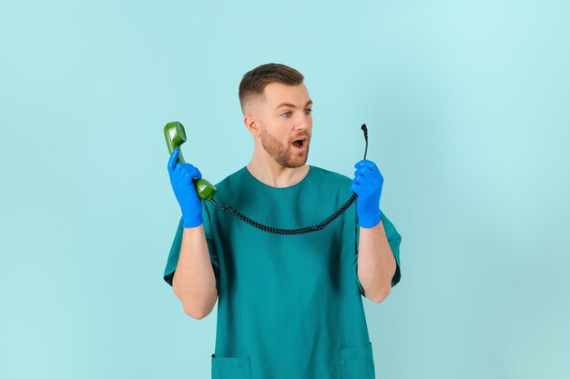 Portret młodego lekarza płci męskiej z telefonem na niebieskim tle