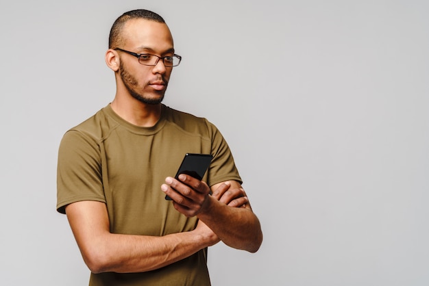 Portret młodego mężczyzny Afroamerykanów w okularach, trzymając telefon komórkowy