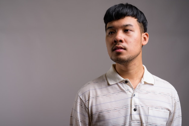 Portret młodego mężczyzny Azji przeciwko szarości