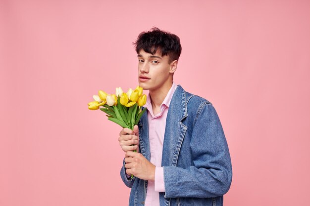 Portret młodego mężczyzny bukiet żółtych kwiatów prezent wakacje elegancki styl różowe tło niezmienione