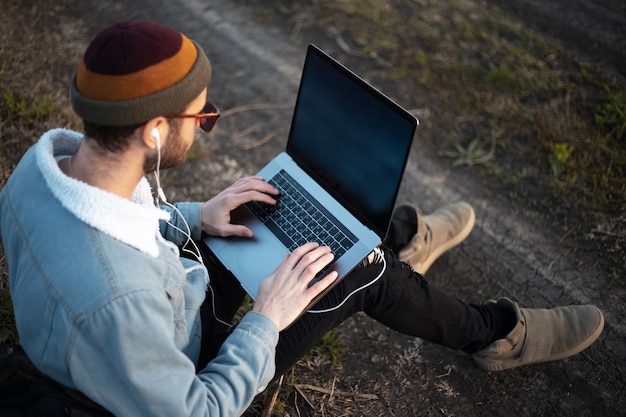 Portret młodego mężczyzny hipster za pomocą laptopa na zewnątrz