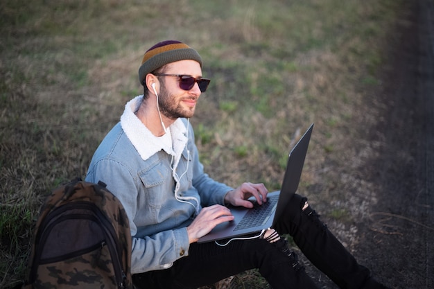 Portret młodego mężczyzny hipster za pomocą laptopa na zewnątrz