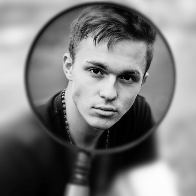 Portret młodego mężczyzny przez szkło powiększające. Czarny i biały