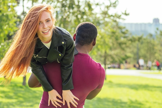 Portret młodego mężczyzny przytulającego swoją dziewczynę stojącego razem w parku wiosna lato w słoneczny dzień