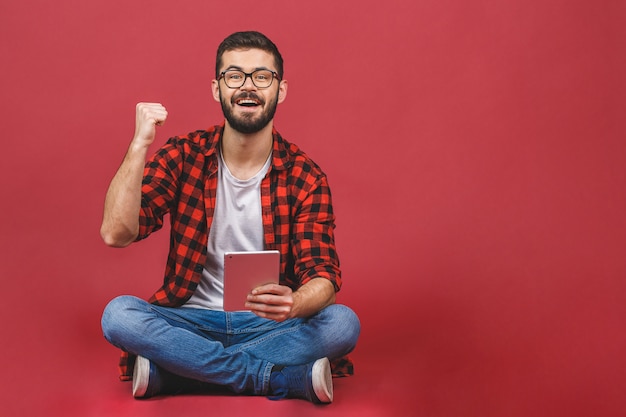 Portret młodego mężczyzny siedzącego na podłodze za pomocą tabletu