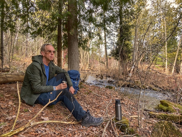 Zdjęcie portret młodego mężczyzny siedzącego w lesie