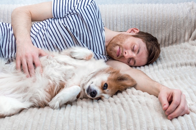 Portret młodego mężczyzny śpiącego z psem w uścisku na łóżku