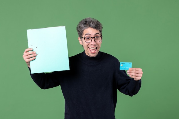 portret młodego mężczyzny trzymającego dokument i kartę kredytową na zielonym tle natura praca bank pieniądze nauczyciel