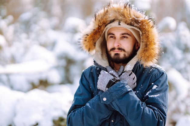 Portret młodego mężczyzny w śnieżnym zimowym lesie Sezon świątecznych podróży i koncepcji ludzi