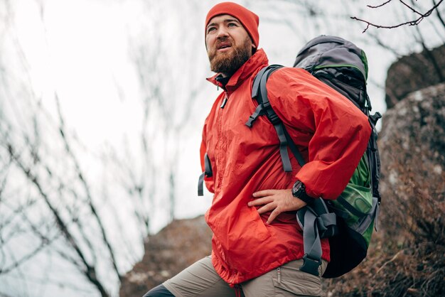 Portret młodego mężczyzny wędrówki w górach ubranych w czerwone ubrania odkrywania nowego miejsca Brodaty mężczyzna podróżujący trekking i alpinizm podczas podróży Podróże ludzie koncepcja sportu i stylu życia
