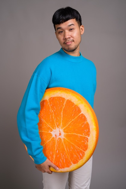 Portret młodego mężczyzny z Azji posiadających duży plasterek pomarańczy
