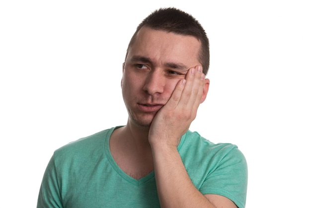 Portret młodego mężczyzny z problemem wrażliwych zębów ból korony cierpiących na ból, dotykając poza usta ręką na białym tle