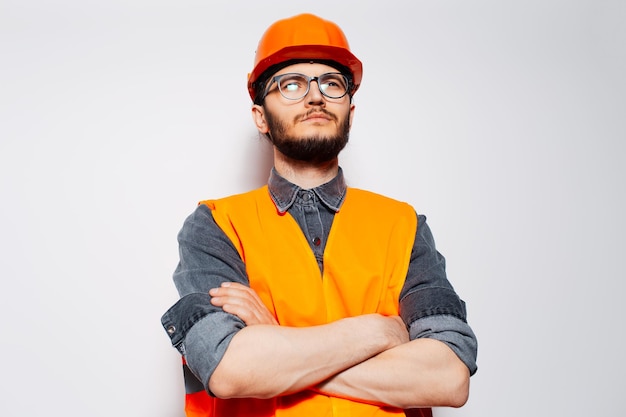 Portret młodego pracownika budowlanego ze skrzyżowanymi rękami na białym tle