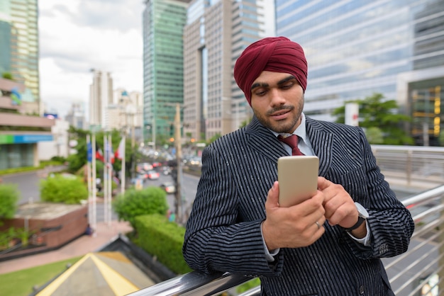 Portret młodego przystojnego indyjskiego biznesmena Sikhów w turbanie podczas zwiedzania miasta Bangkok, Tajlandia
